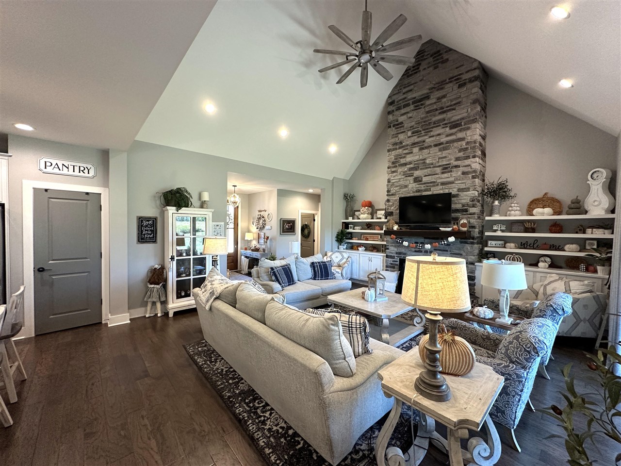 Furnished living room with a vaulted ceiling and tall stone fireplace.