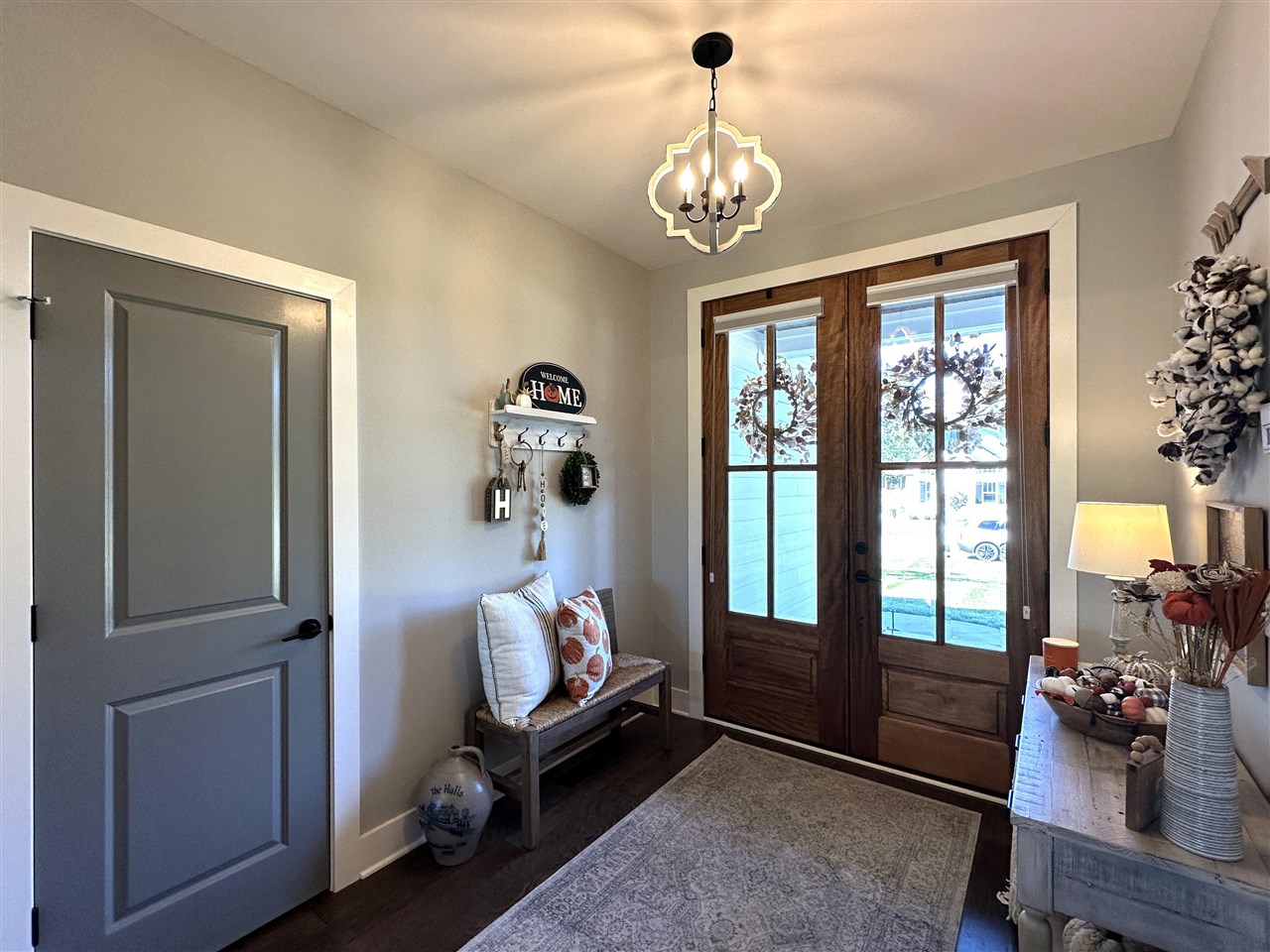 Furnished foyer with glass-paneled double doors, a cushioned bench, and a patterned rug.