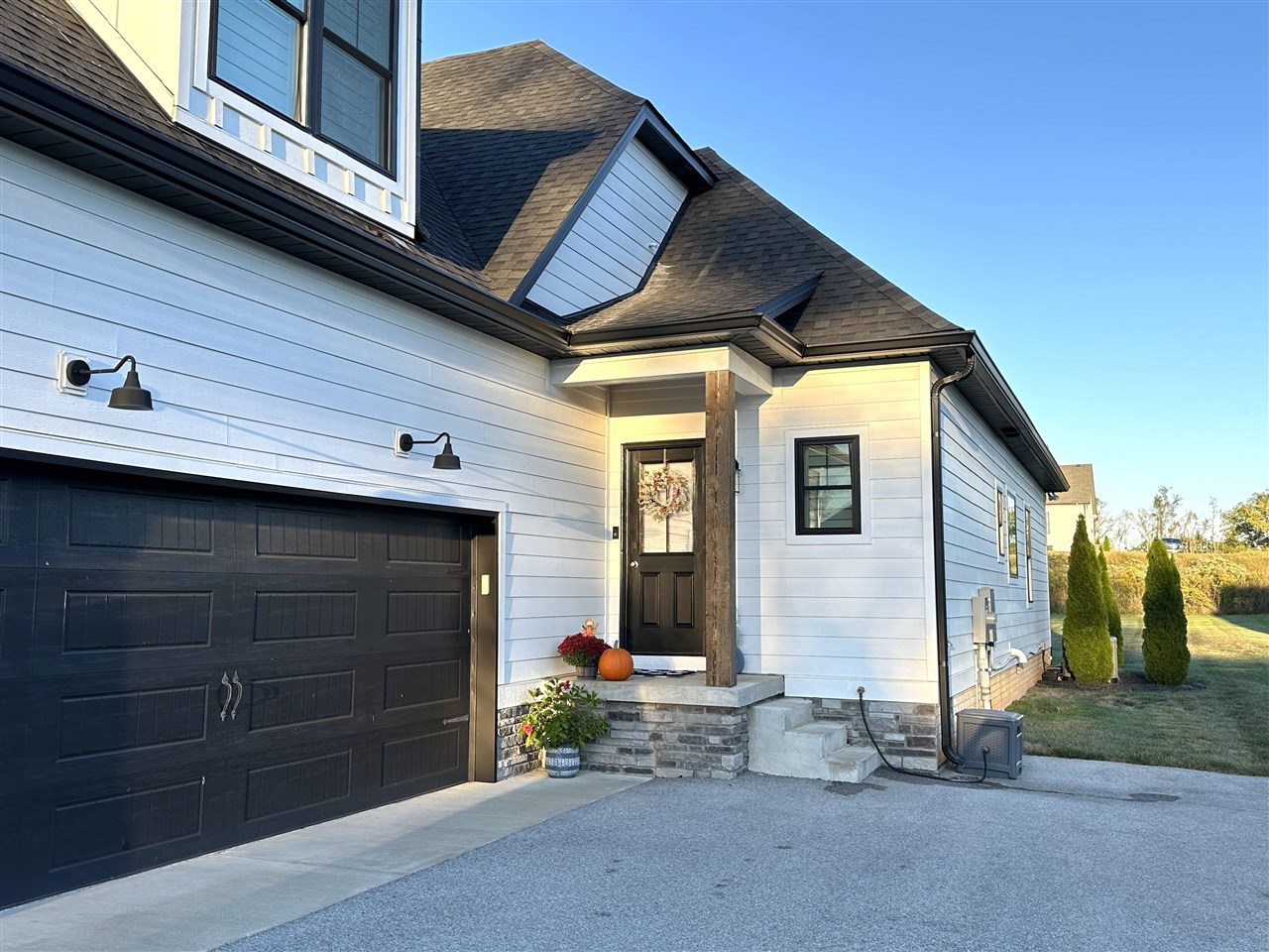 White two-story home with black garage door and stone-front covered entry.