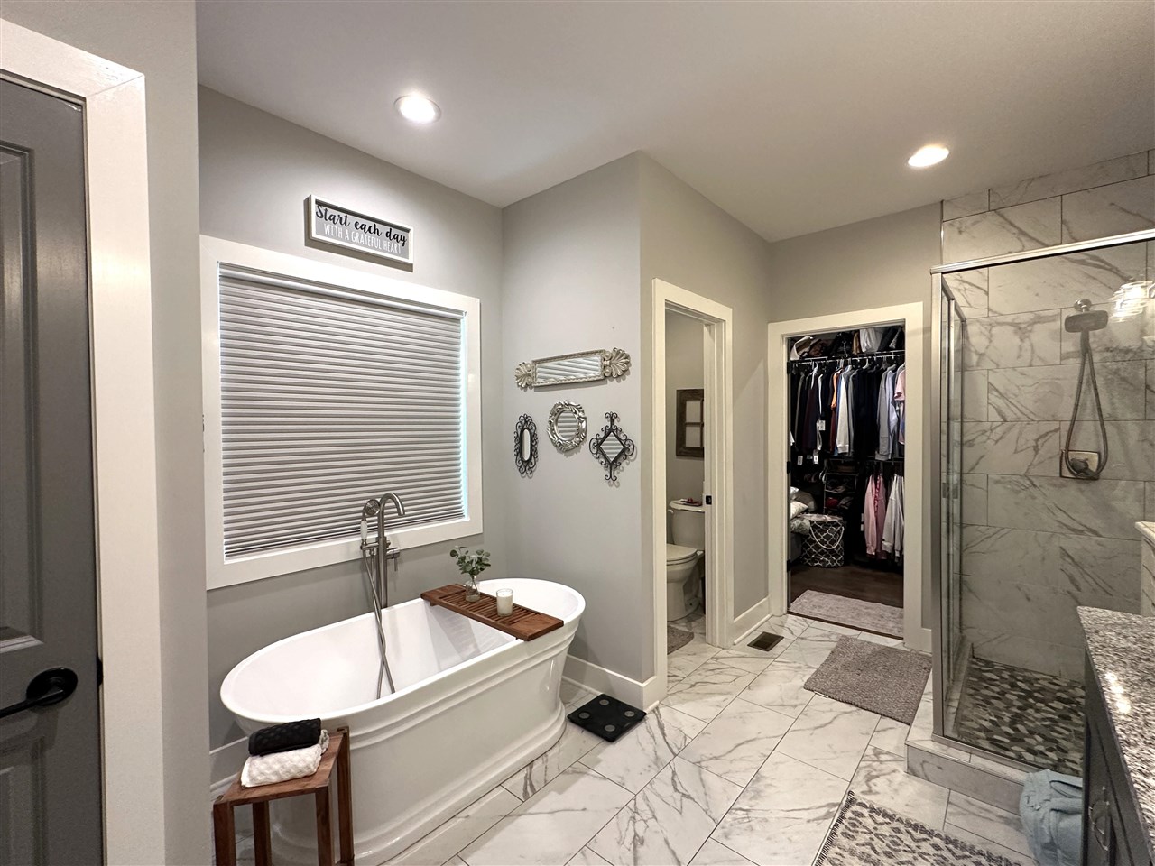 Bathroom with a freestanding soaking tub, marble-look tile, and glass-enclosed shower.