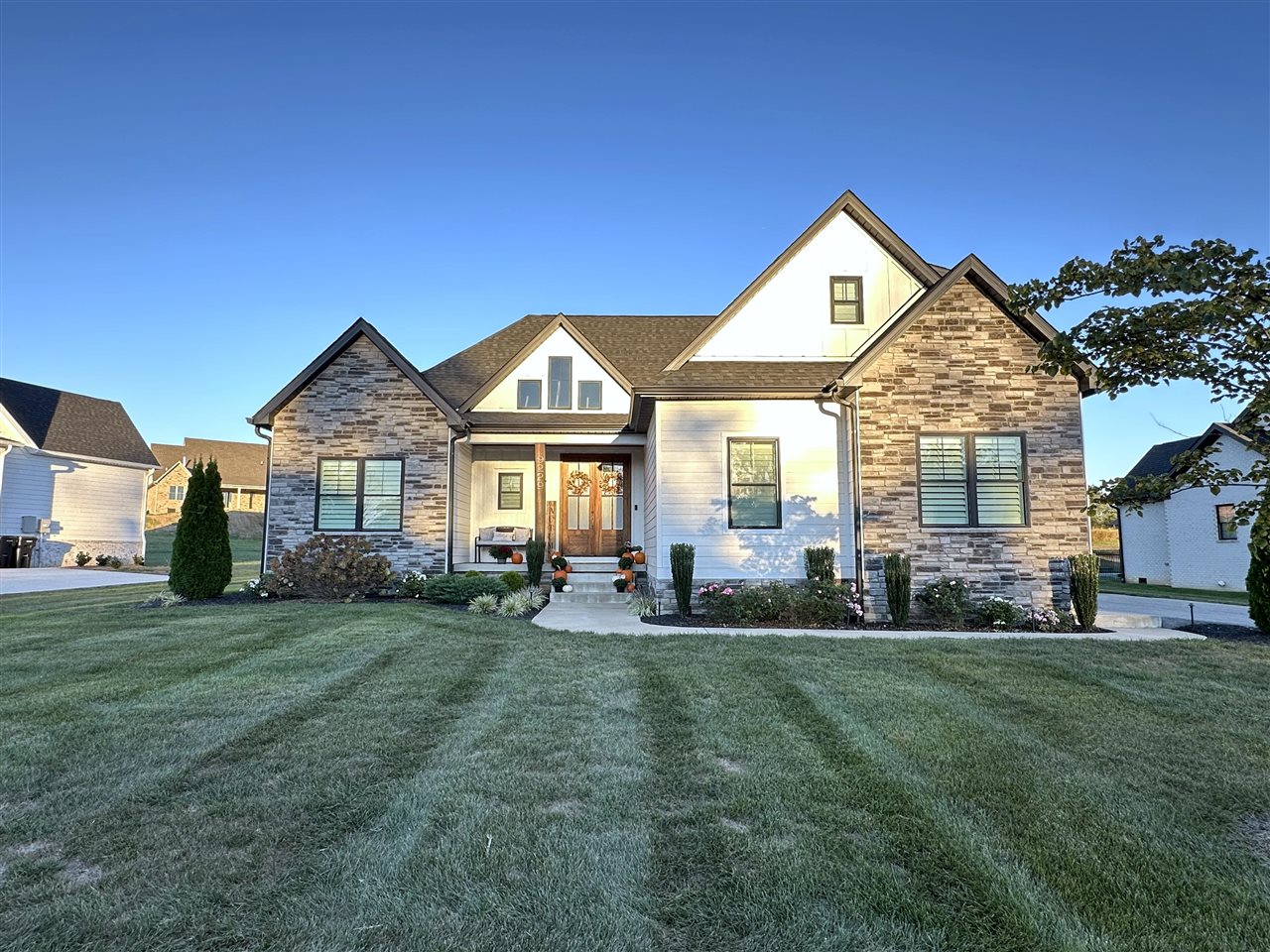 Home with stone and white siding, multiple gables, and a landscaped front lawn.
