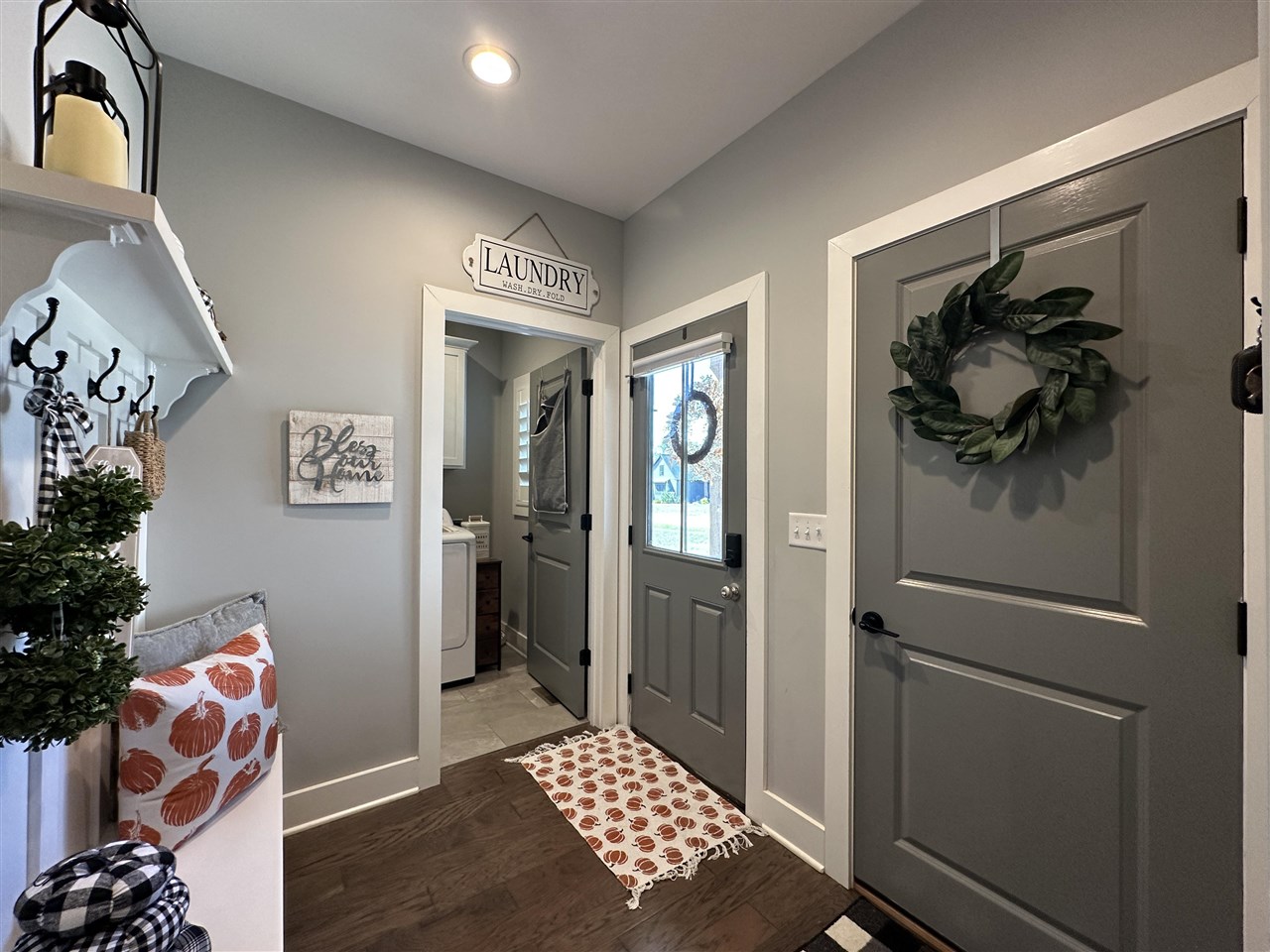 Entry hall with gray paneled doors, a wreath, and an open doorway to the laundry room.