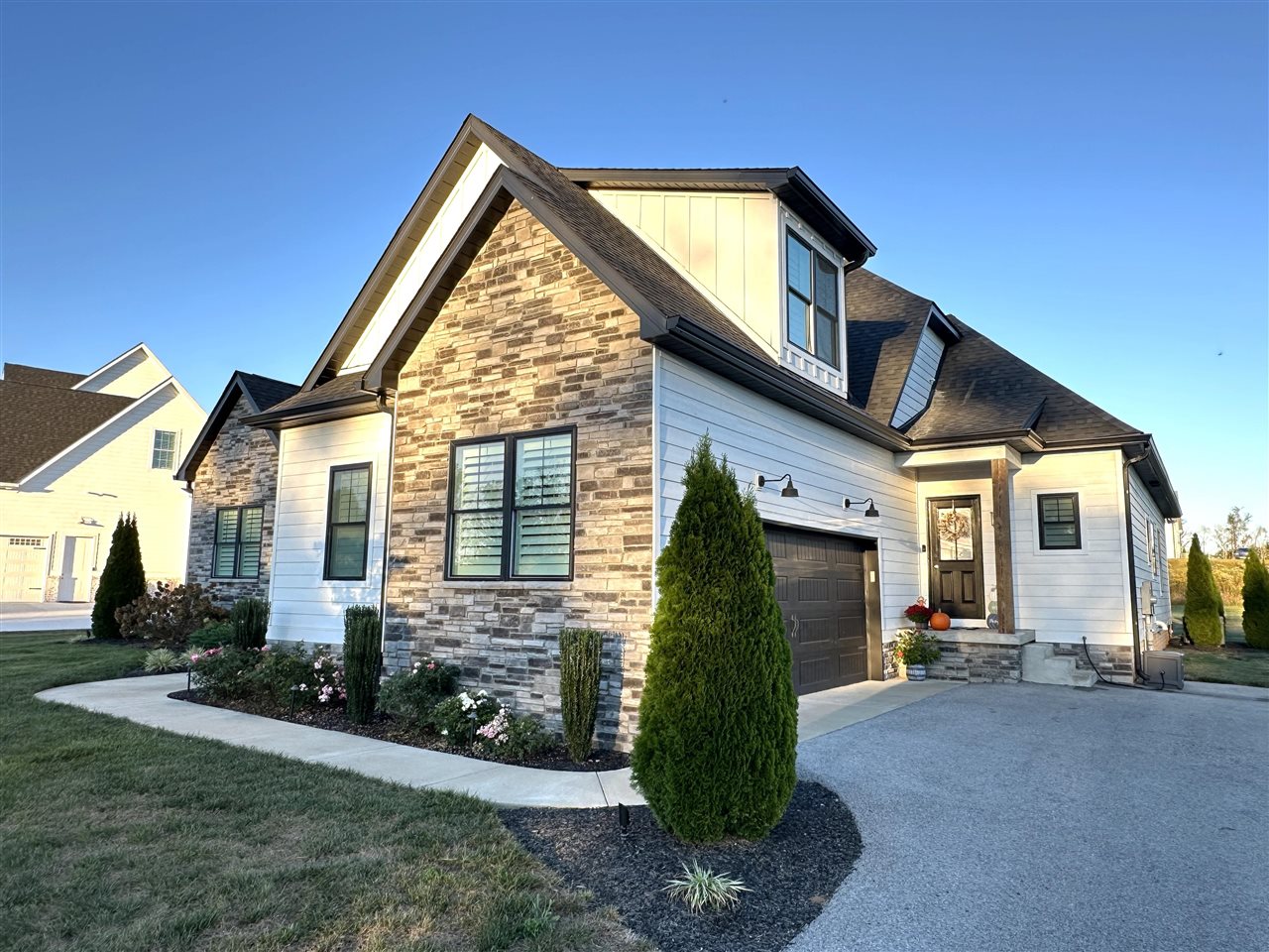 Two-story home with a stone facade, white siding, and landscaped front garden.