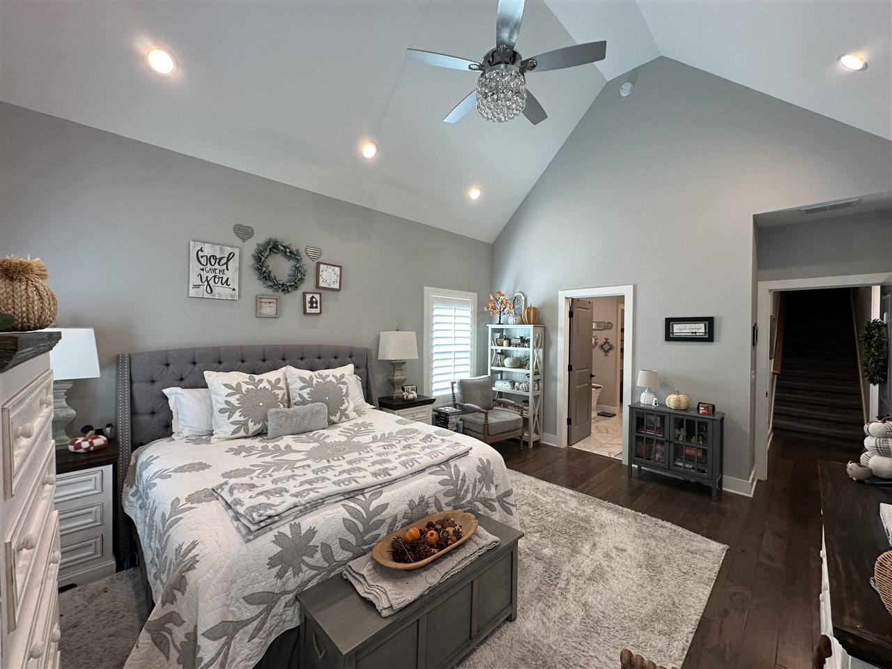 Furnished bedroom with patterned bedding, a vaulted ceiling, and a ceiling fan.