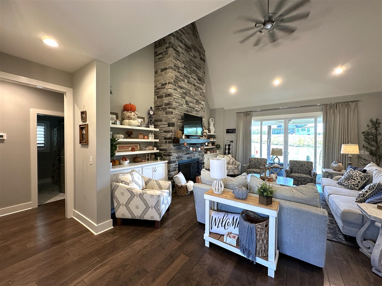 Furnished living room with a floor-to-ceiling stone fireplace, vaulted ceiling, and sliding glass doors.