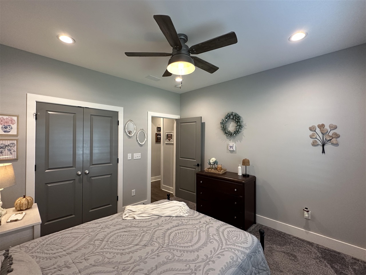 Furnished bedroom with dark closet doors, a ceiling fan, and a dark dresser.