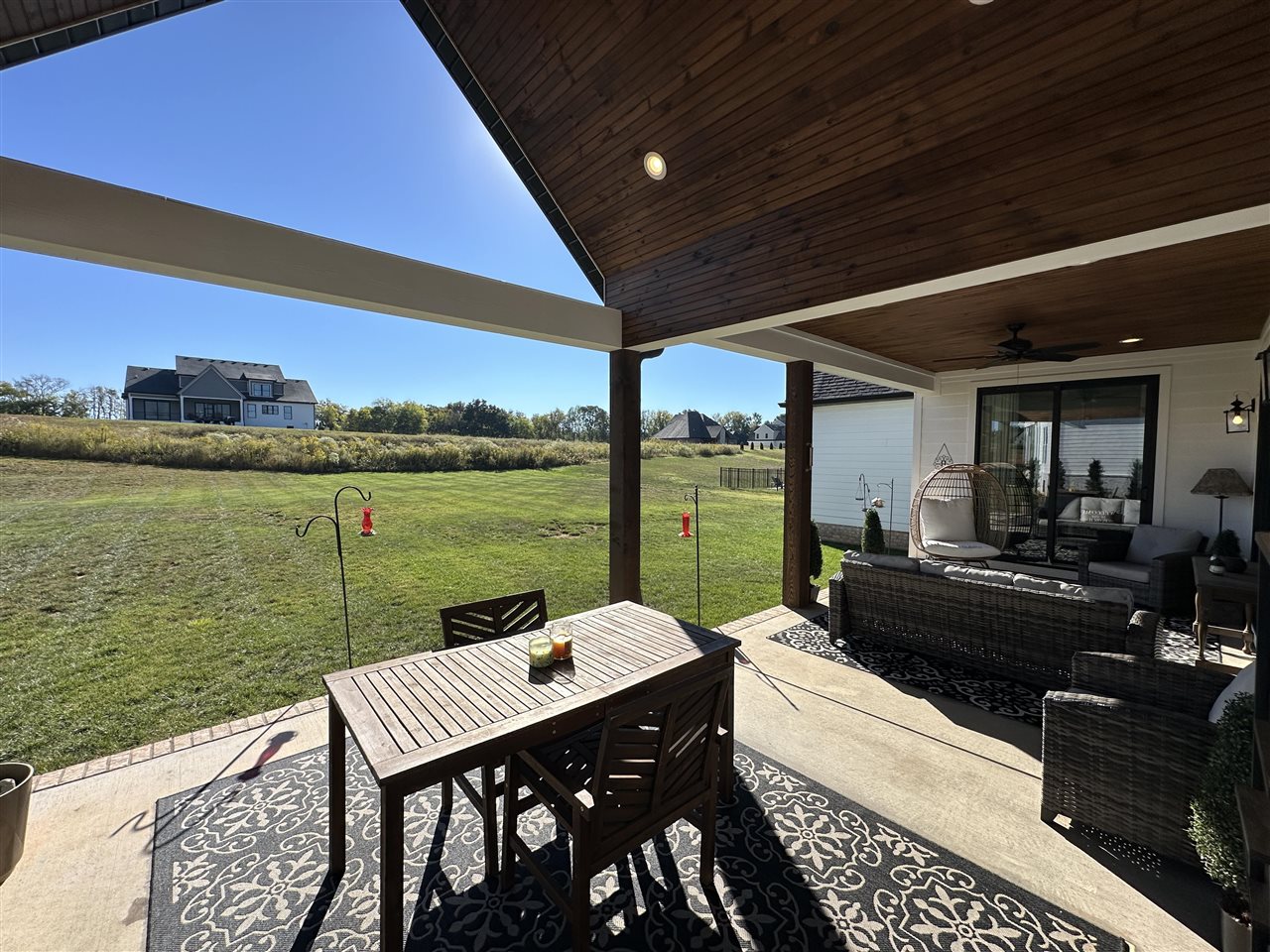 Covered patio with dining and lounge seating overlooking a broad green lawn.