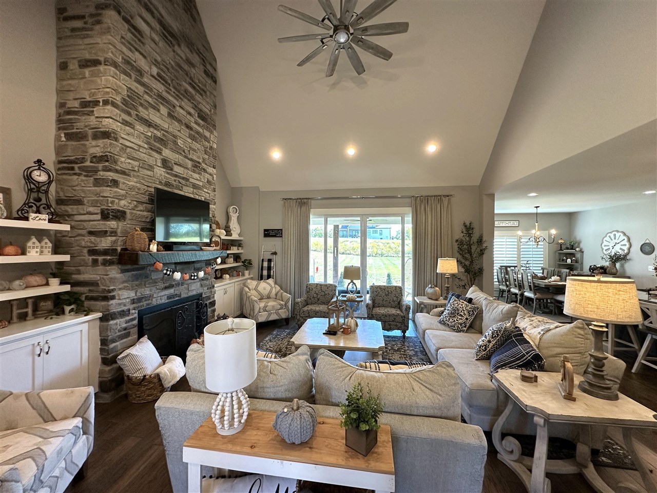 Living room with a tall stone fireplace, vaulted ceiling, and sliding glass doors opening to the garden.