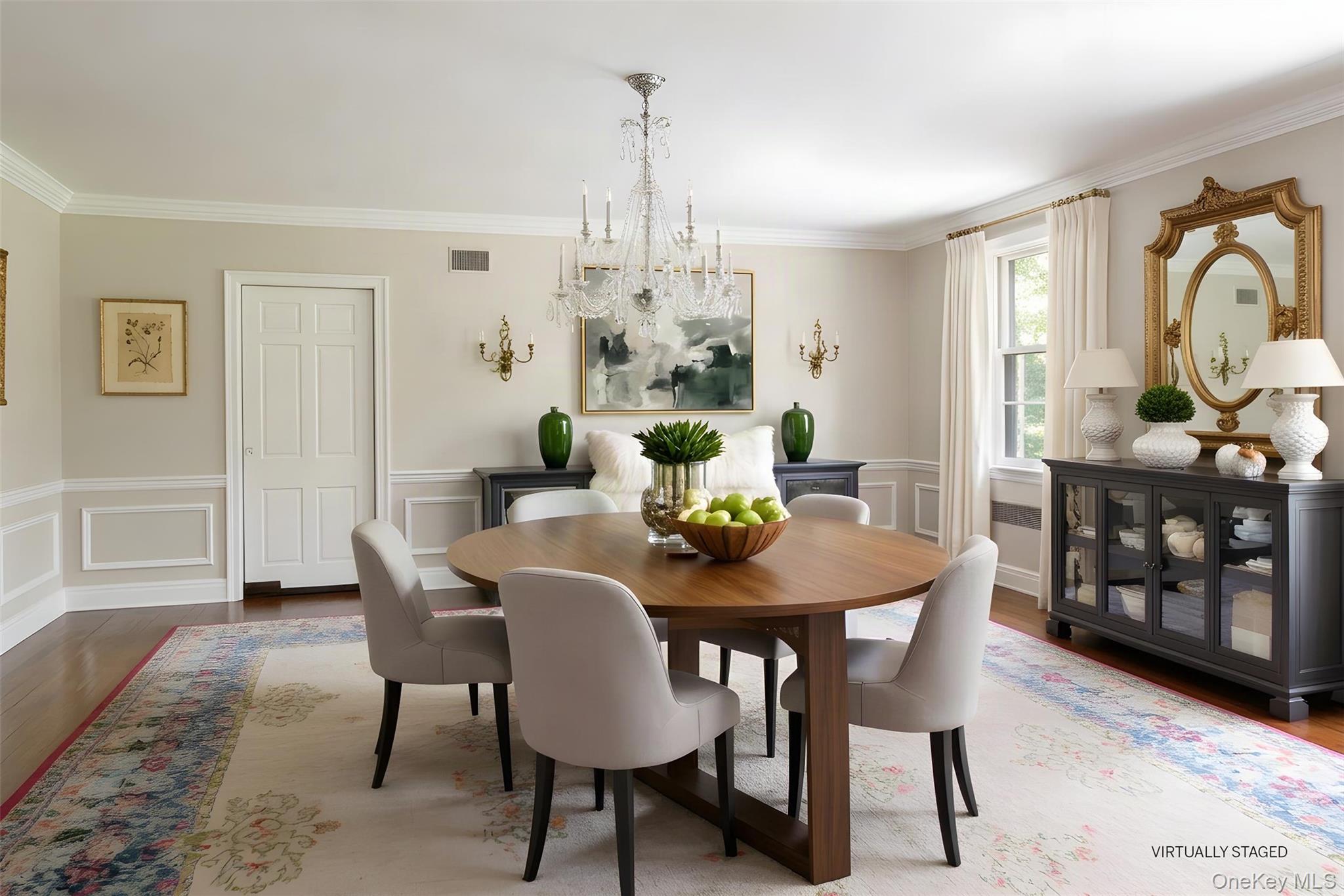 Virtually staged dining room with a round wood table, crystal chandelier, and ornate mirror.