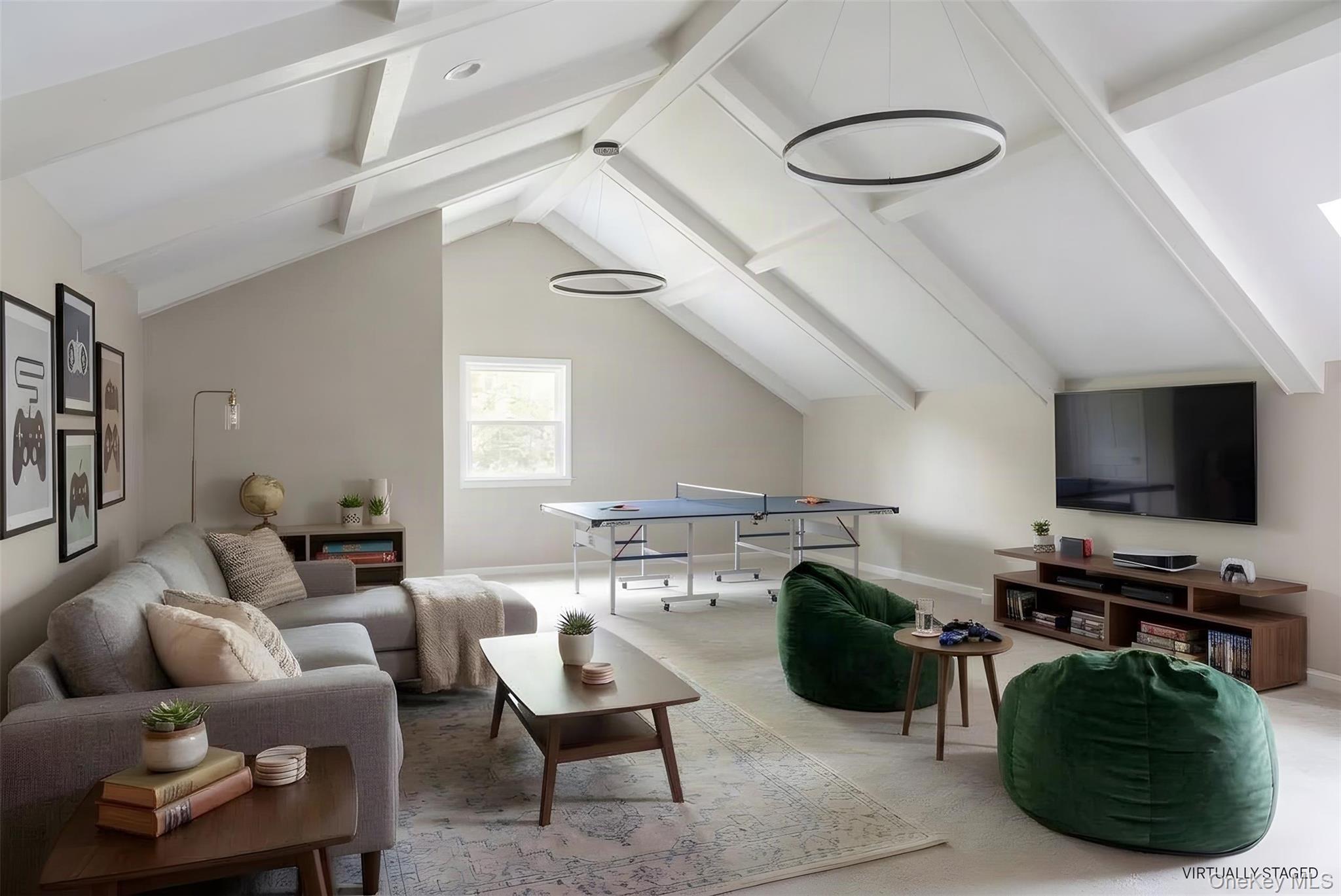 Recreation room with a ping-pong table, vaulted ceiling, gray sofa, and green beanbag chairs.