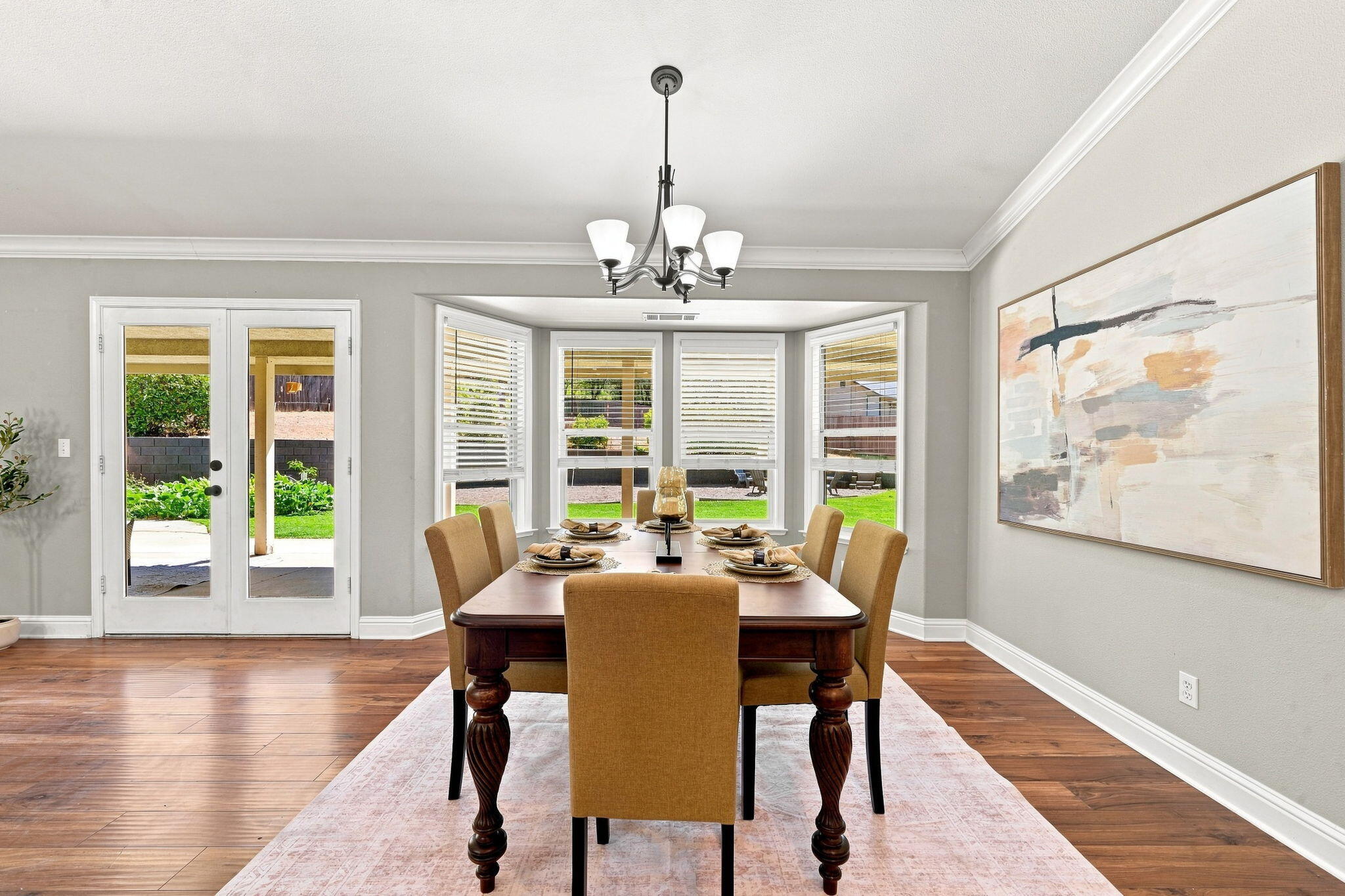 Dining room with a set table, bay windows, and glass doors opening to the backyard.