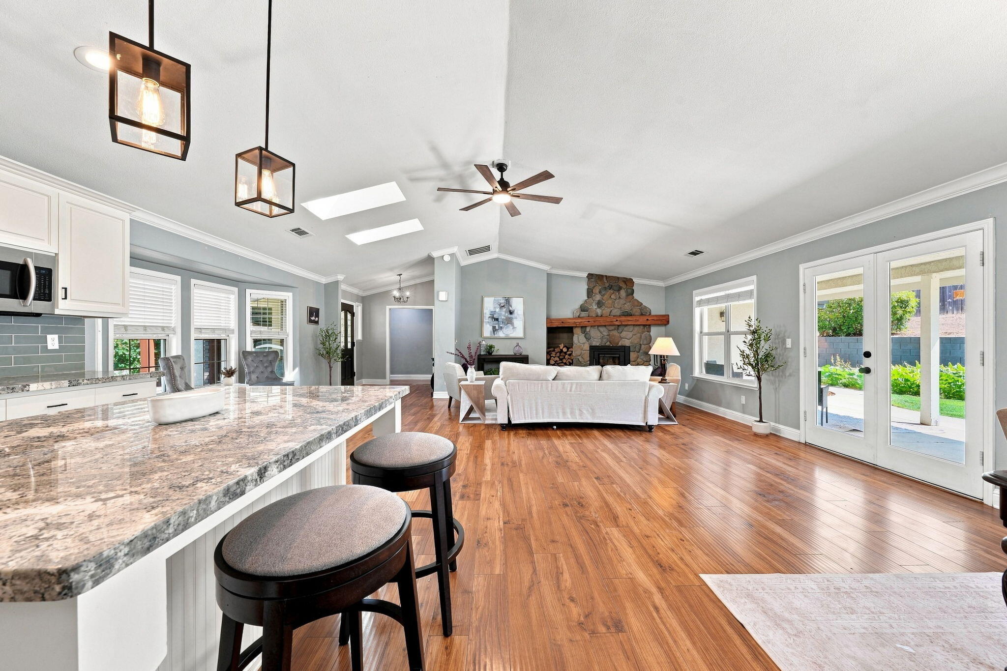 Open-plan kitchen and living room with stone island, vaulted ceiling, and stone fireplace.