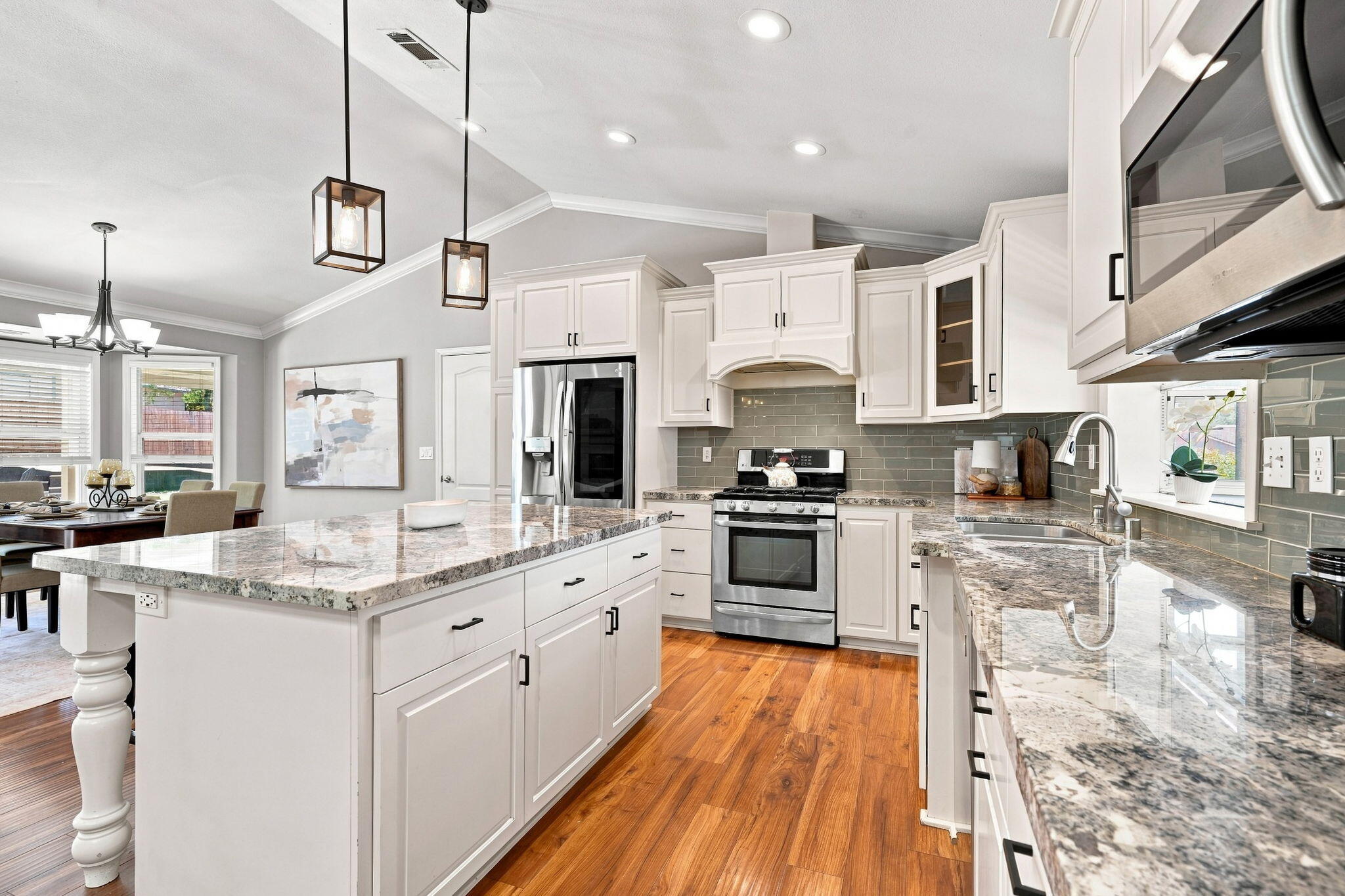 Bright kitchen with white cabinetry, granite counters, stainless steel appliances, and a large island.