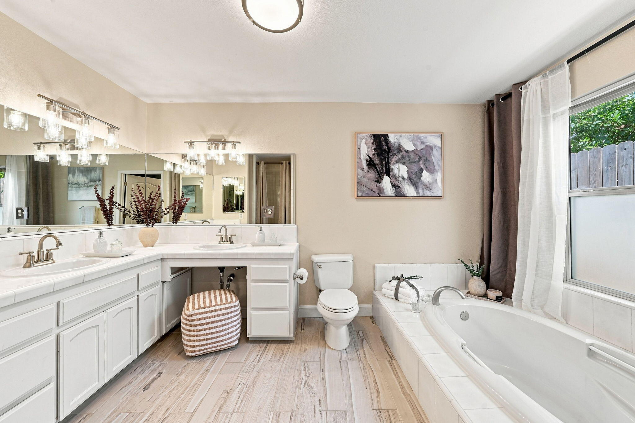 Bathroom with a double vanity, freestanding-style soaking tub, and large mirrored wall.