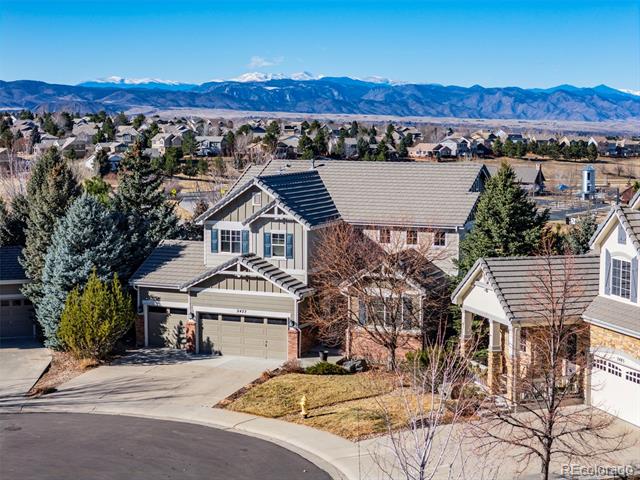 Two-story suburban home with an attached garage, neighboring houses, and snow-capped mountains beyond.