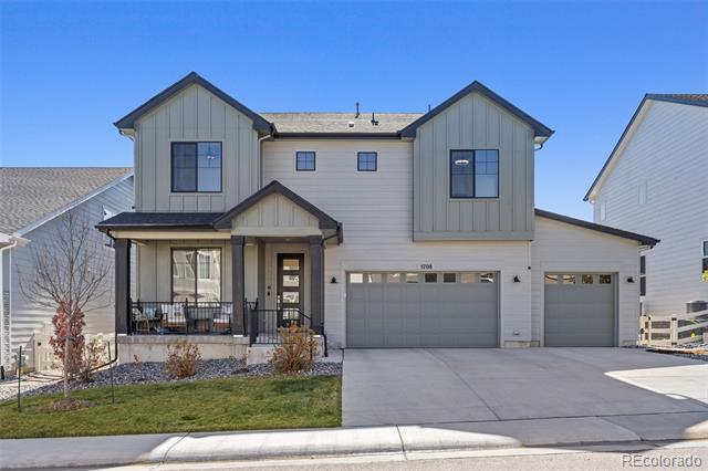 Two-story gray house with a covered porch and wide attached garage.
