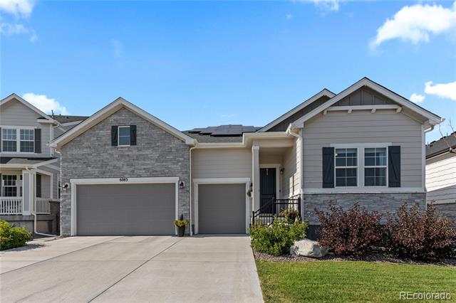 Gray and stone two-story house with three garage doors and a wide concrete driveway.