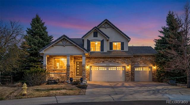 Two-story stone-accented home at dusk, with illuminated windows and a two-car garage.