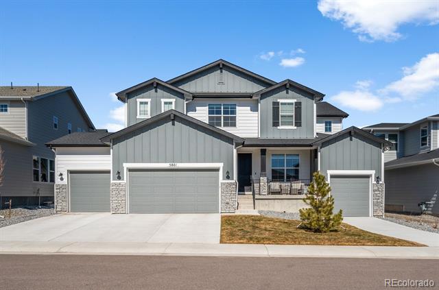 Two-story gray house with three garage doors, a covered porch, and a small front lawn.