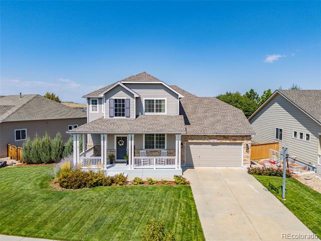 Two-story gray house with a covered porch, attached garage, and landscaped lawn.