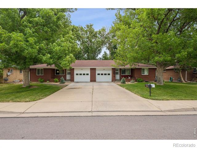 Single-story brick home with two garage doors, a broad driveway, and mature trees.