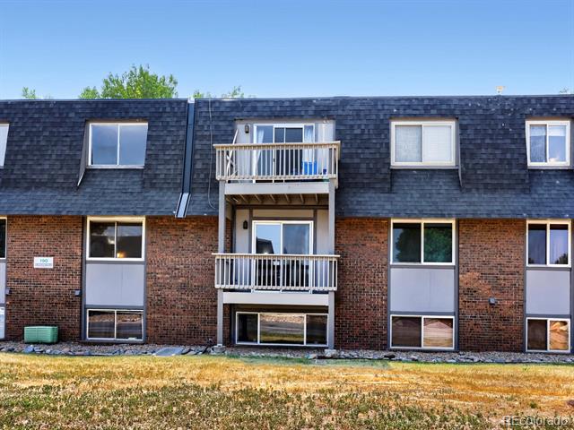 Condominium exterior with red brick, a dark shingle roof, and two stacked white-railed balconies.