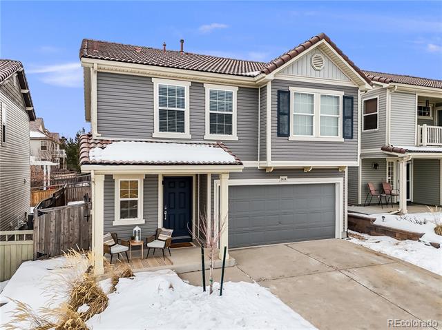 Gray two-story townhouse with an attached garage, dark blue front door, and snow-covered yard.