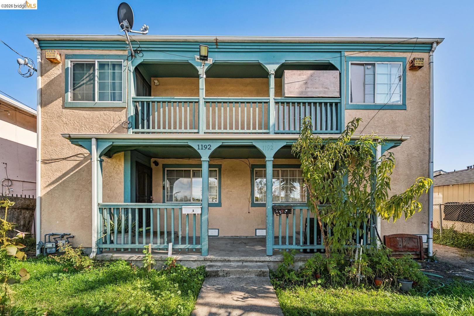 Two-story tan stucco residence with turquoise trim and covered balconies above the front porches.