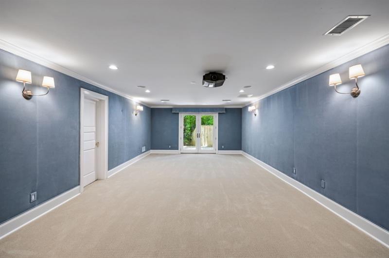 Empty home theater with blue walls, beige carpet, and a ceiling-mounted projector.