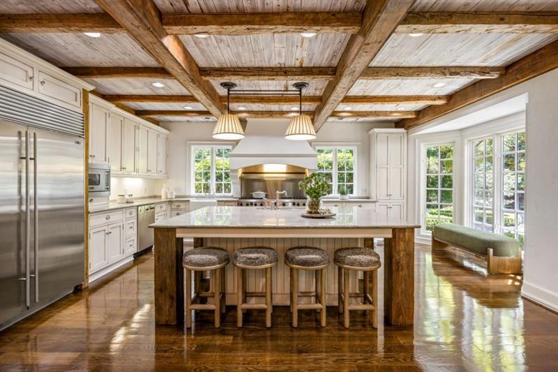 Bright kitchen with a large island, exposed wood ceiling beams, and a window bench.
