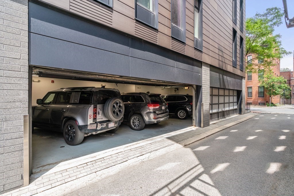 Modern building with an open garage entrance and cars parked inside.