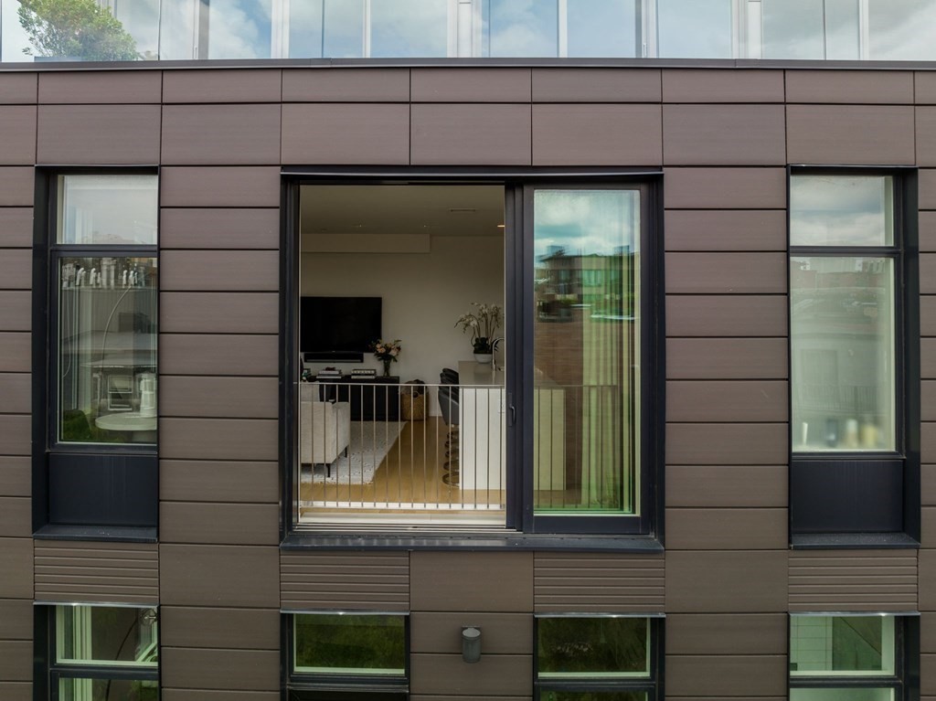 Modern apartment facade with an open sliding door revealing a furnished living room.