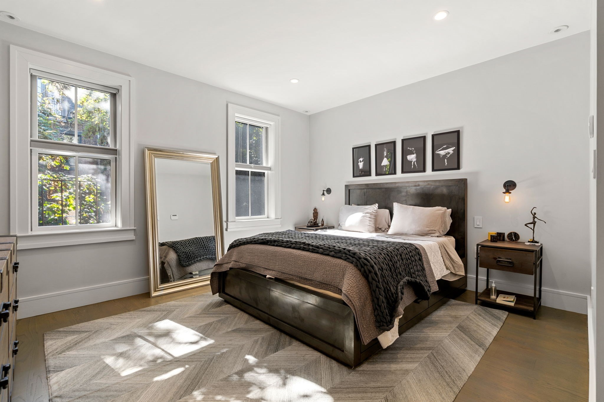 Bedroom with a dark wood bed, tall windows, and framed ballet prints above the headboard.