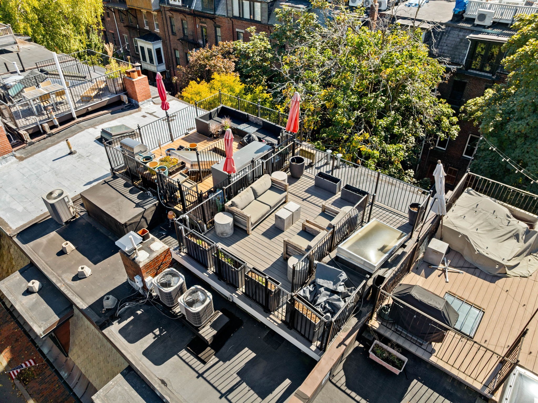 Rooftop terrace with wood decking, outdoor seating, planters, and red umbrellas.