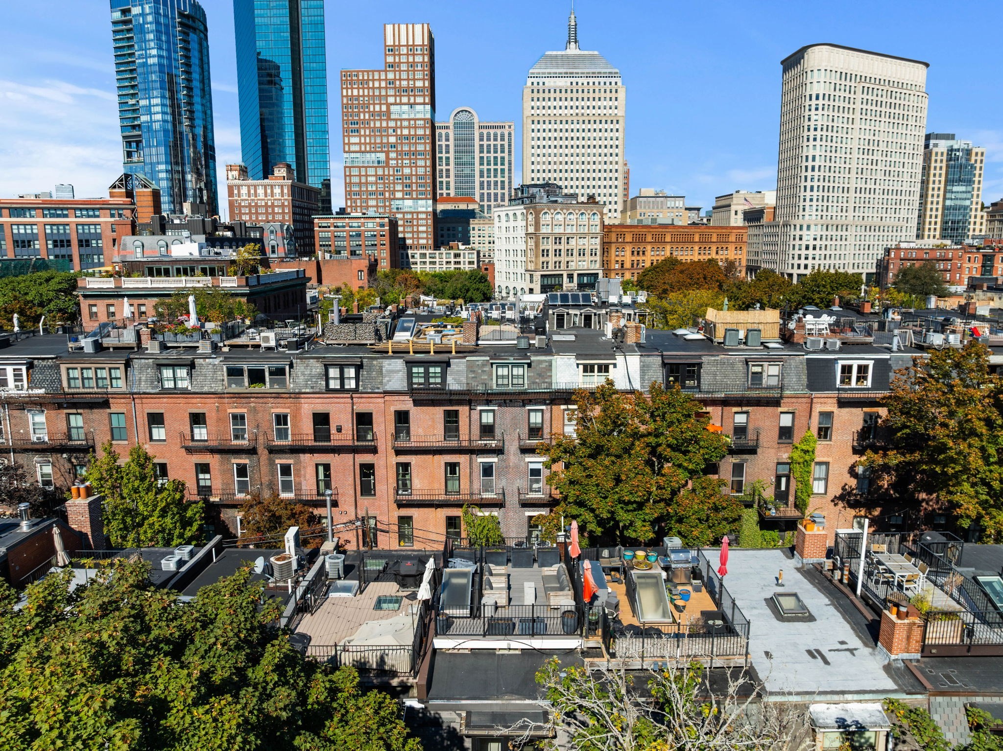 Rooftop terraces and brick residences with the Boston skyline behind them.