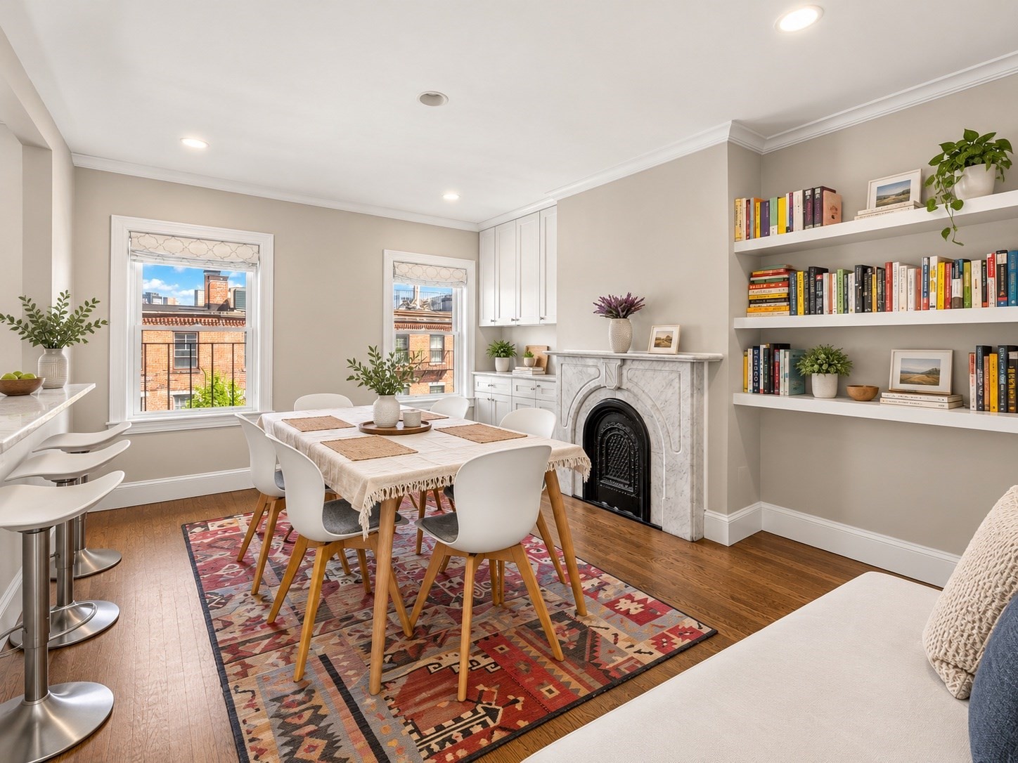 Dining room with a marble fireplace, built-in bookcases, and large windows.