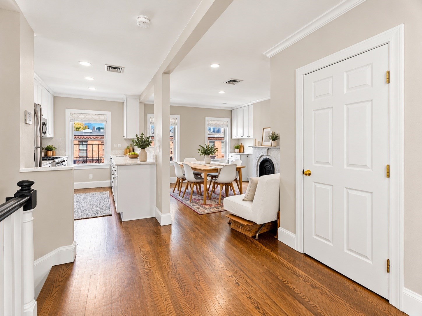 Open kitchen and dining area with hardwood floors, white cabinetry, and a fireplace.