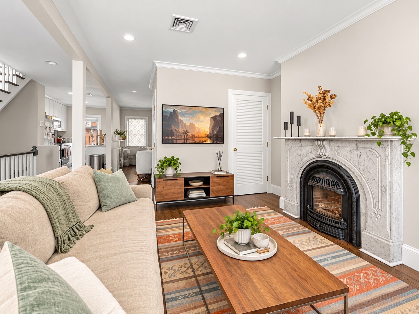 Furnished living room with an ornate marble fireplace, beige sofa, and wooden coffee table.