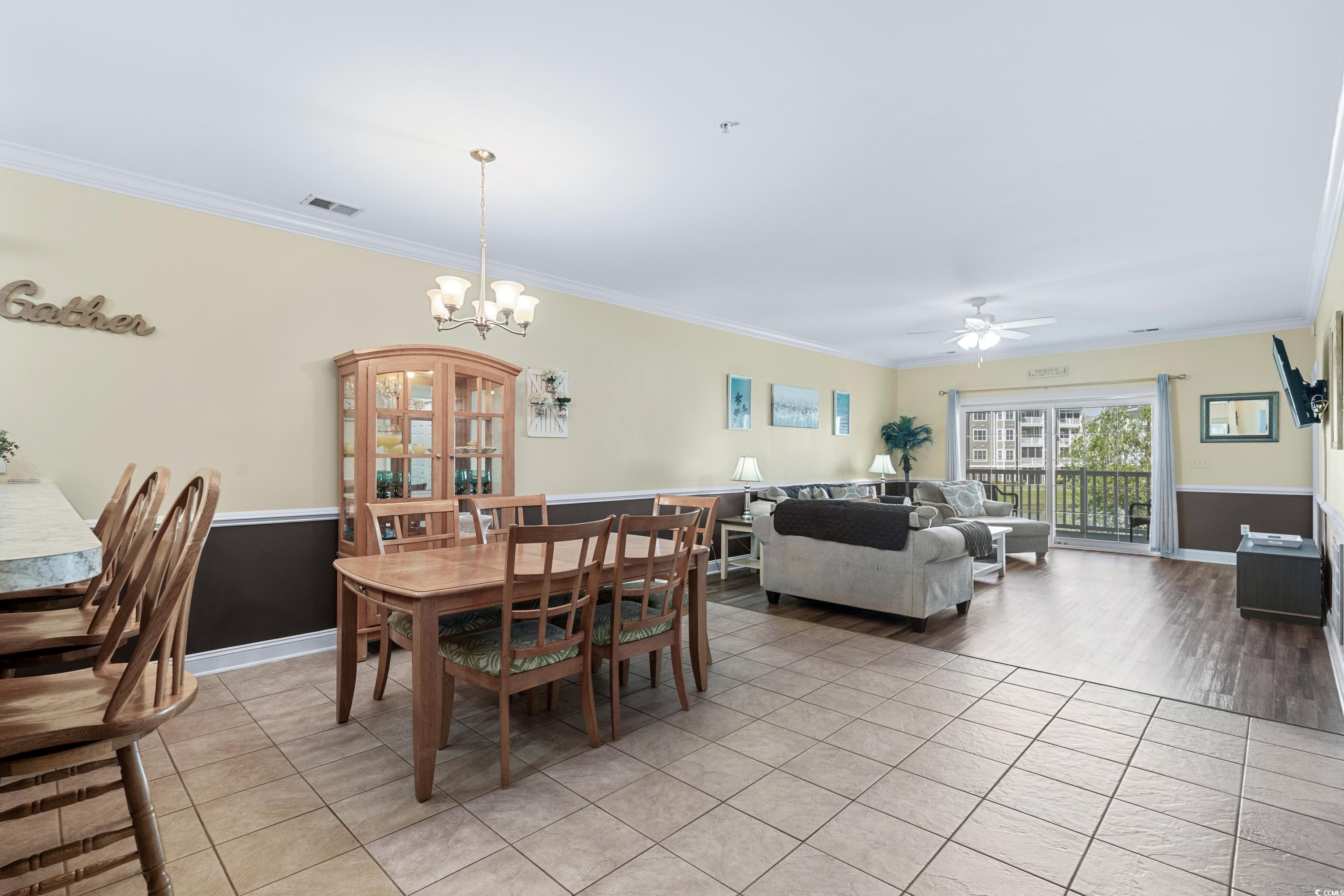 Open-plan dining and living room with a wooden dining set, gray sectional, and sliding doors to a balcony.