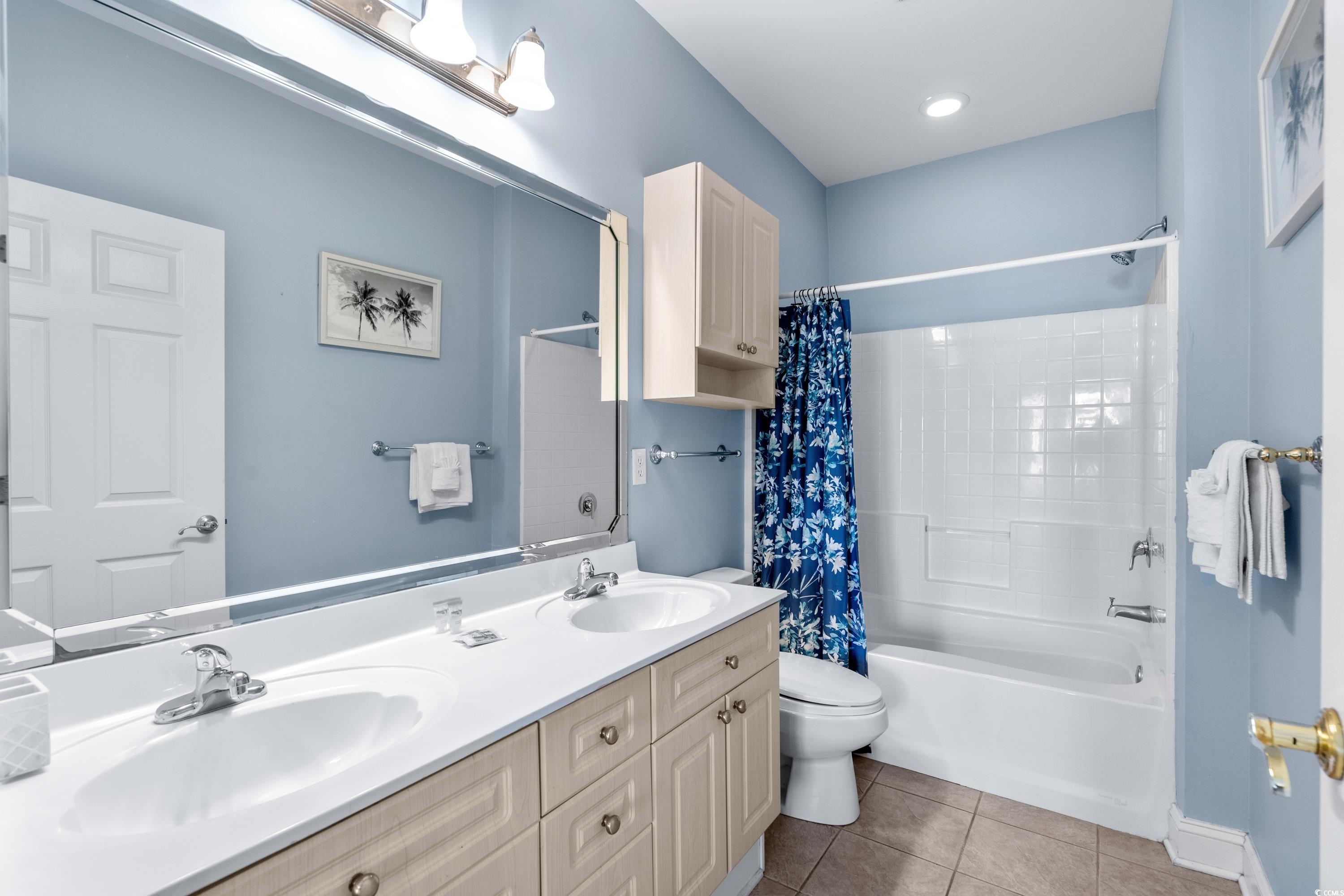 Bathroom with a double-sink vanity, white tub, and blue floral shower curtain.