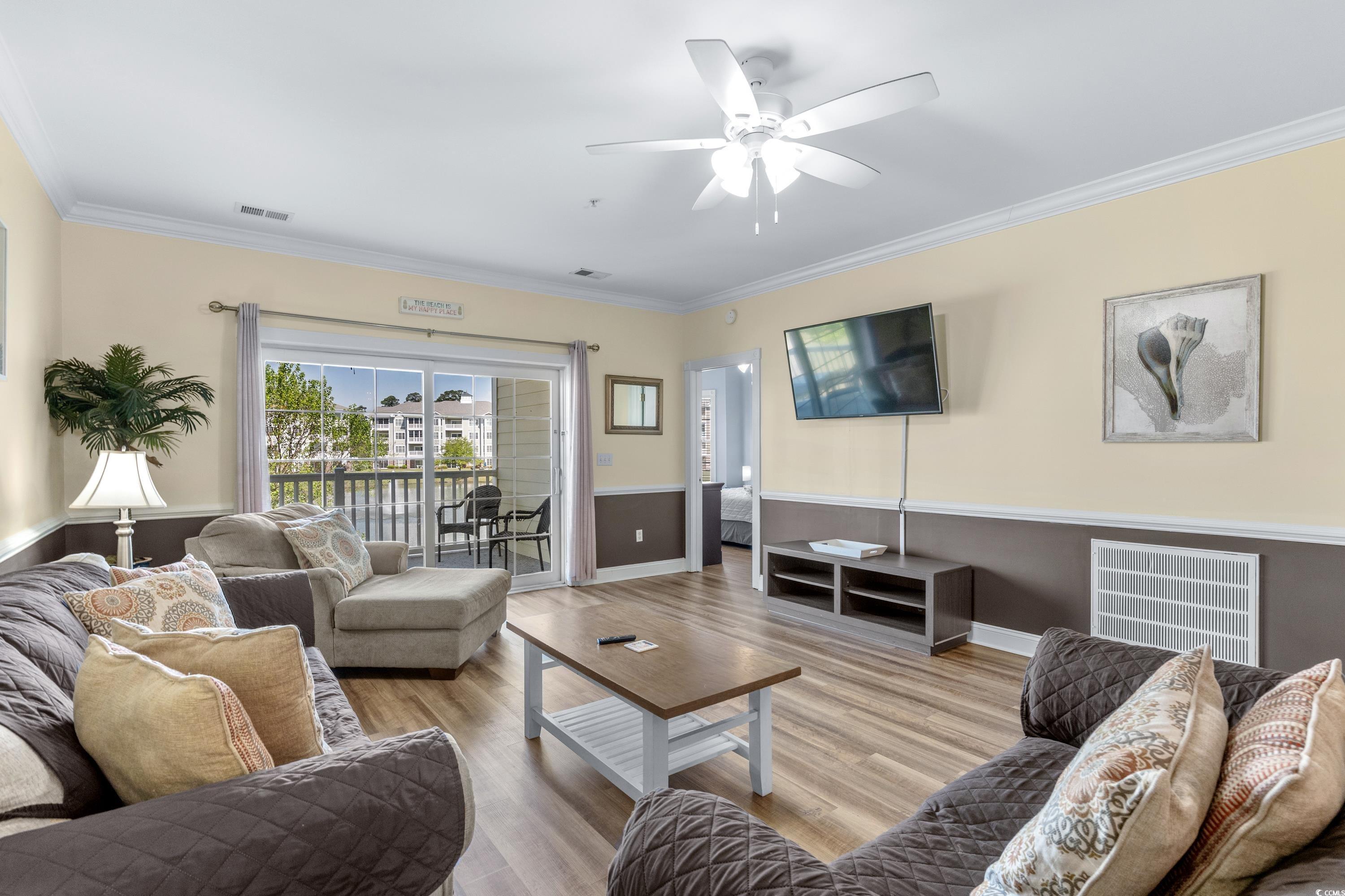 Furnished living room with sliding glass doors to a balcony and a wall-mounted television.