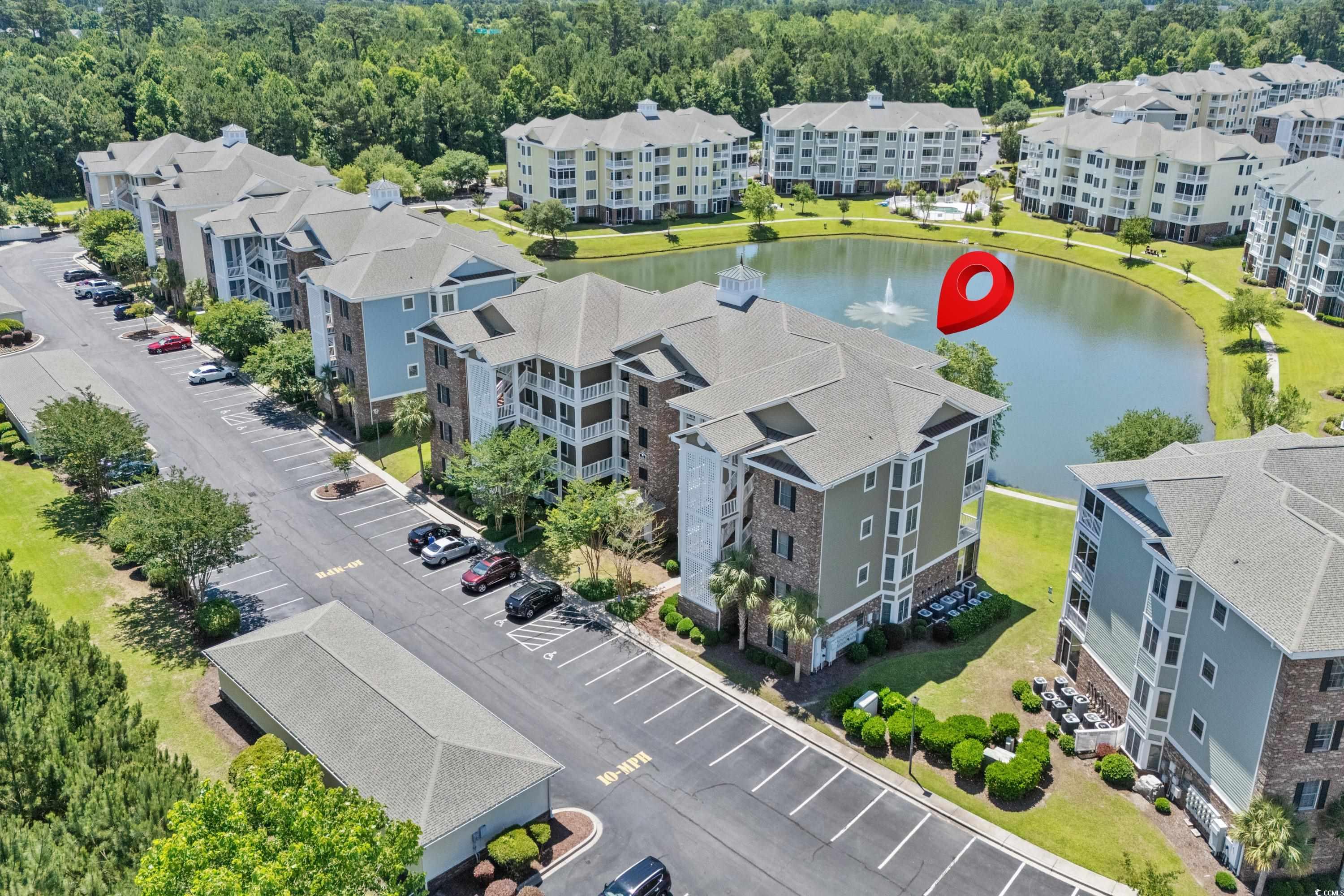 Aerial view of apartment buildings around a pond, with a red location pin marking the community.