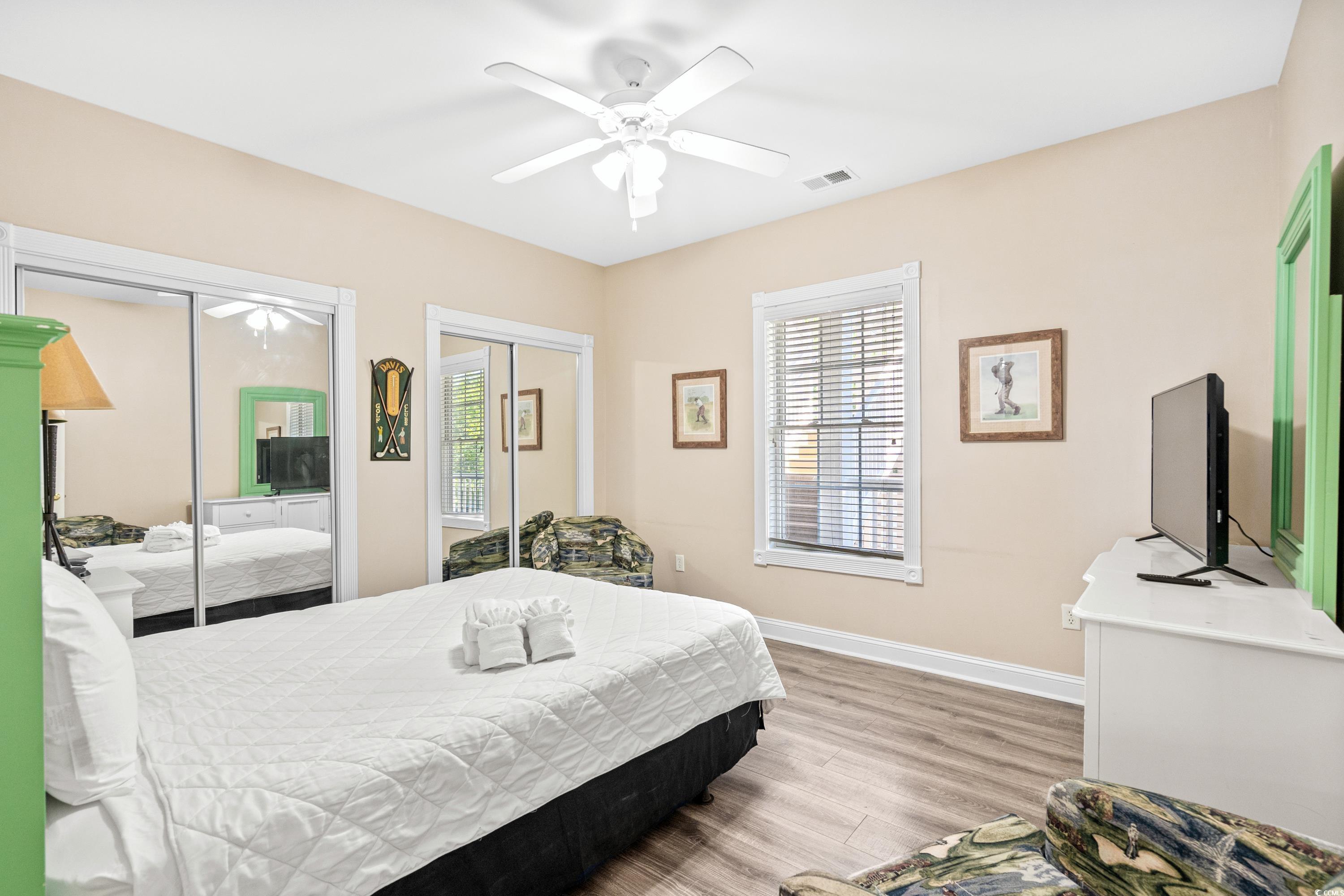 Furnished bedroom with mirrored closet doors, a white bed, and bright green trim.