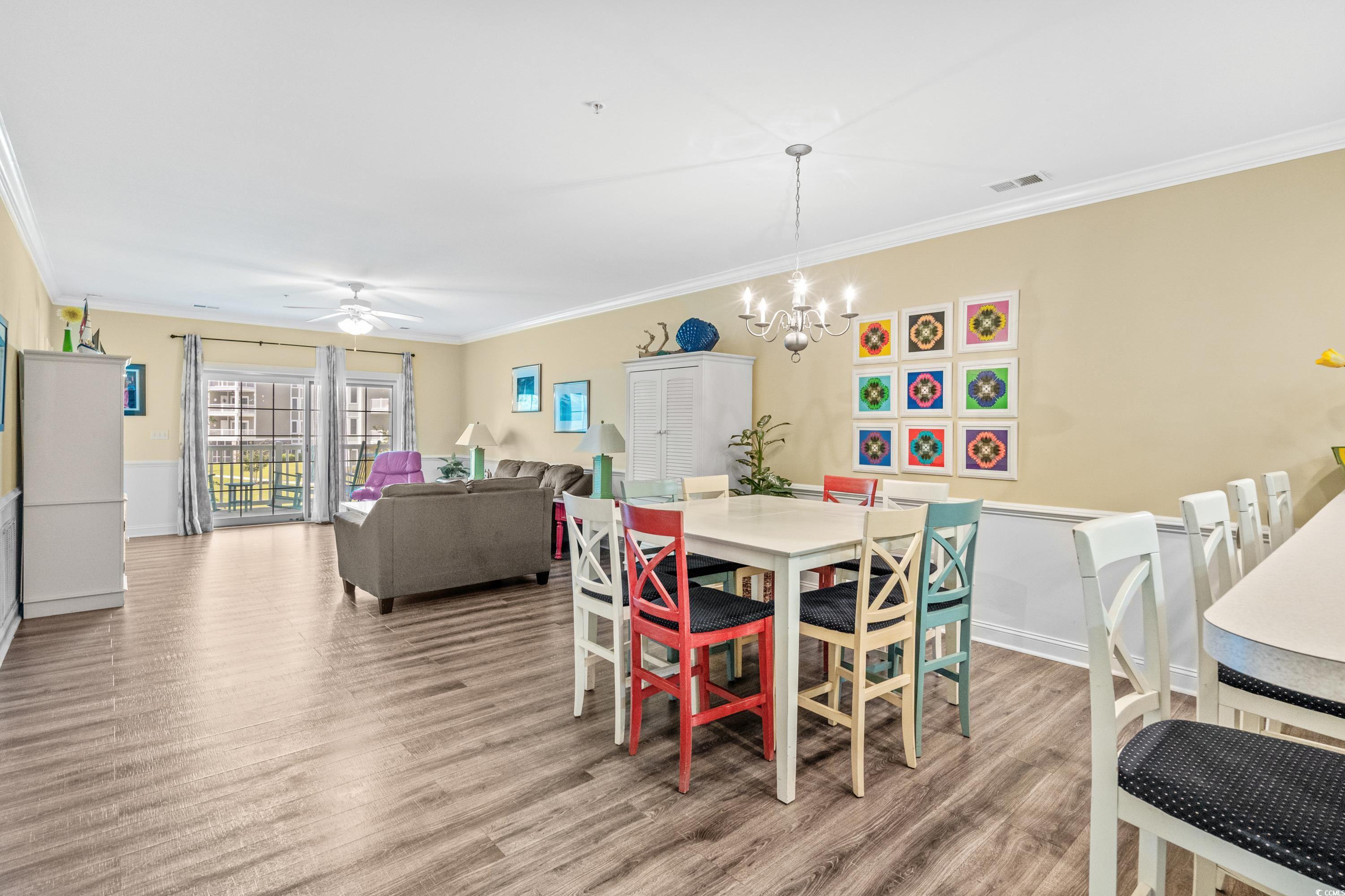 Open-plan dining and living room with colorful dining chairs and sliding doors to a balcony.