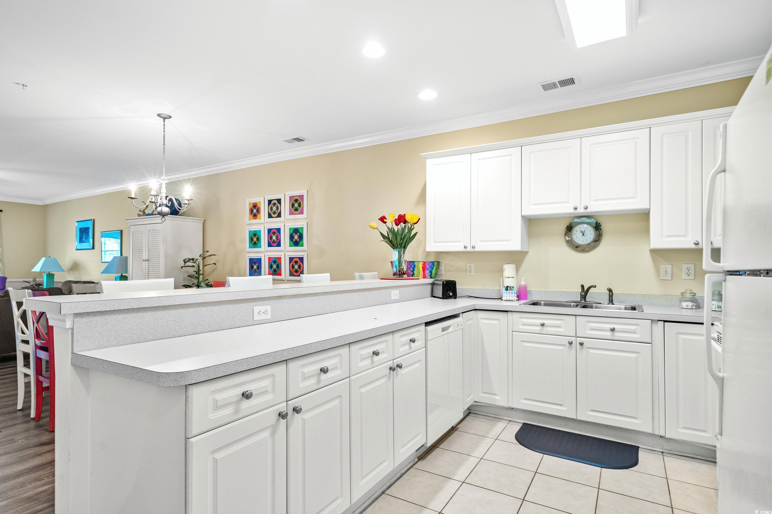 Kitchen with white cabinetry, a long peninsula counter, and a double-basin sink.