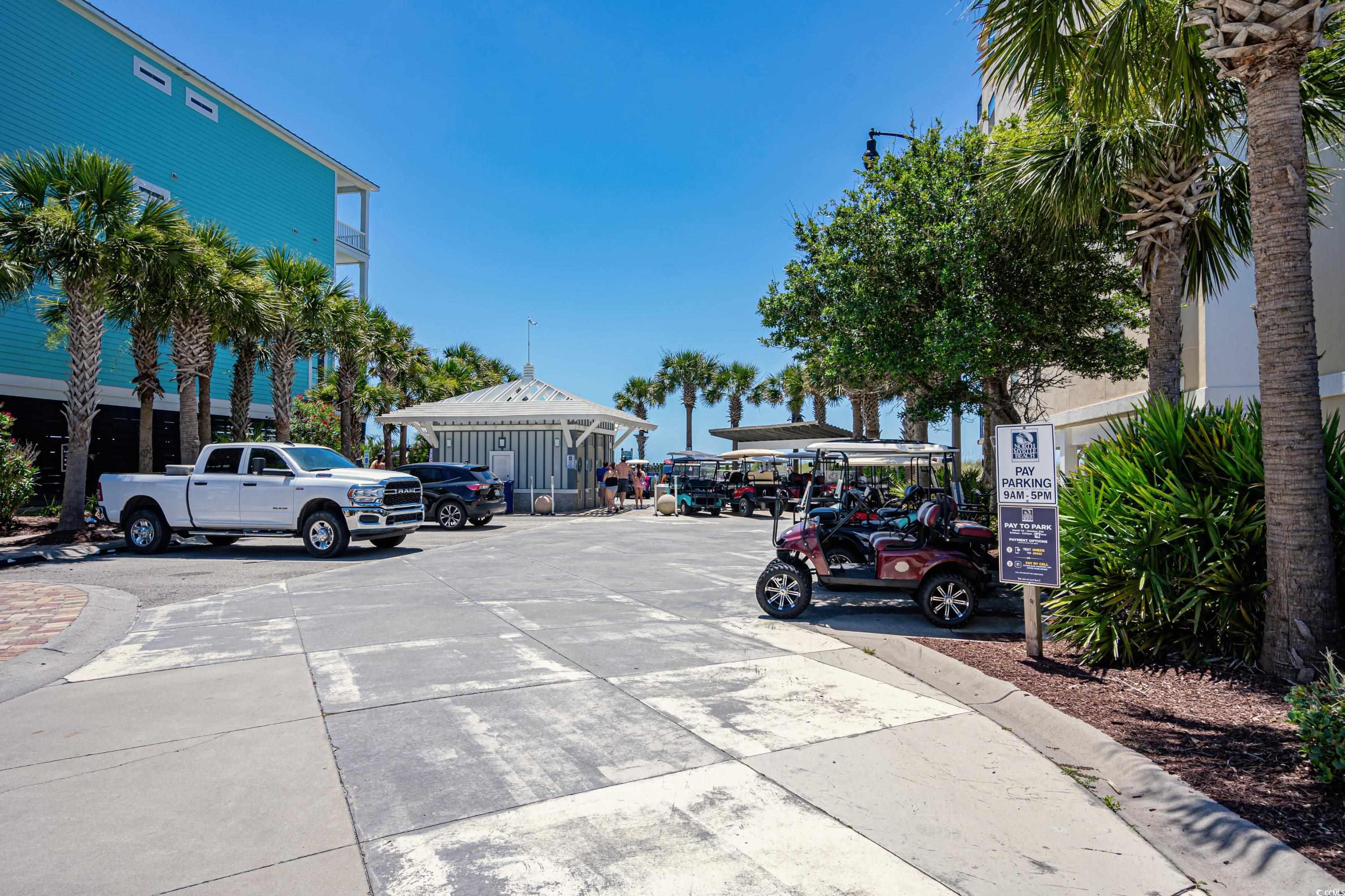 Condominium entrance and parking area lined with palm trees and golf carts.