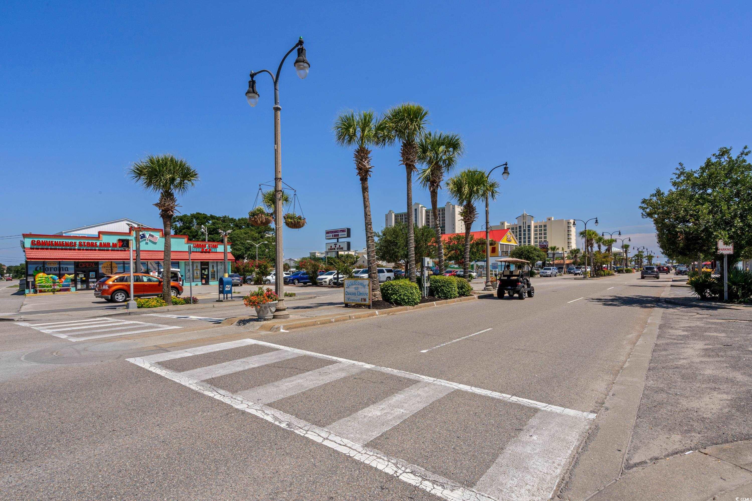 Ocean Drive street scene with palm trees, a crosswalk, shops, and condominium buildings.