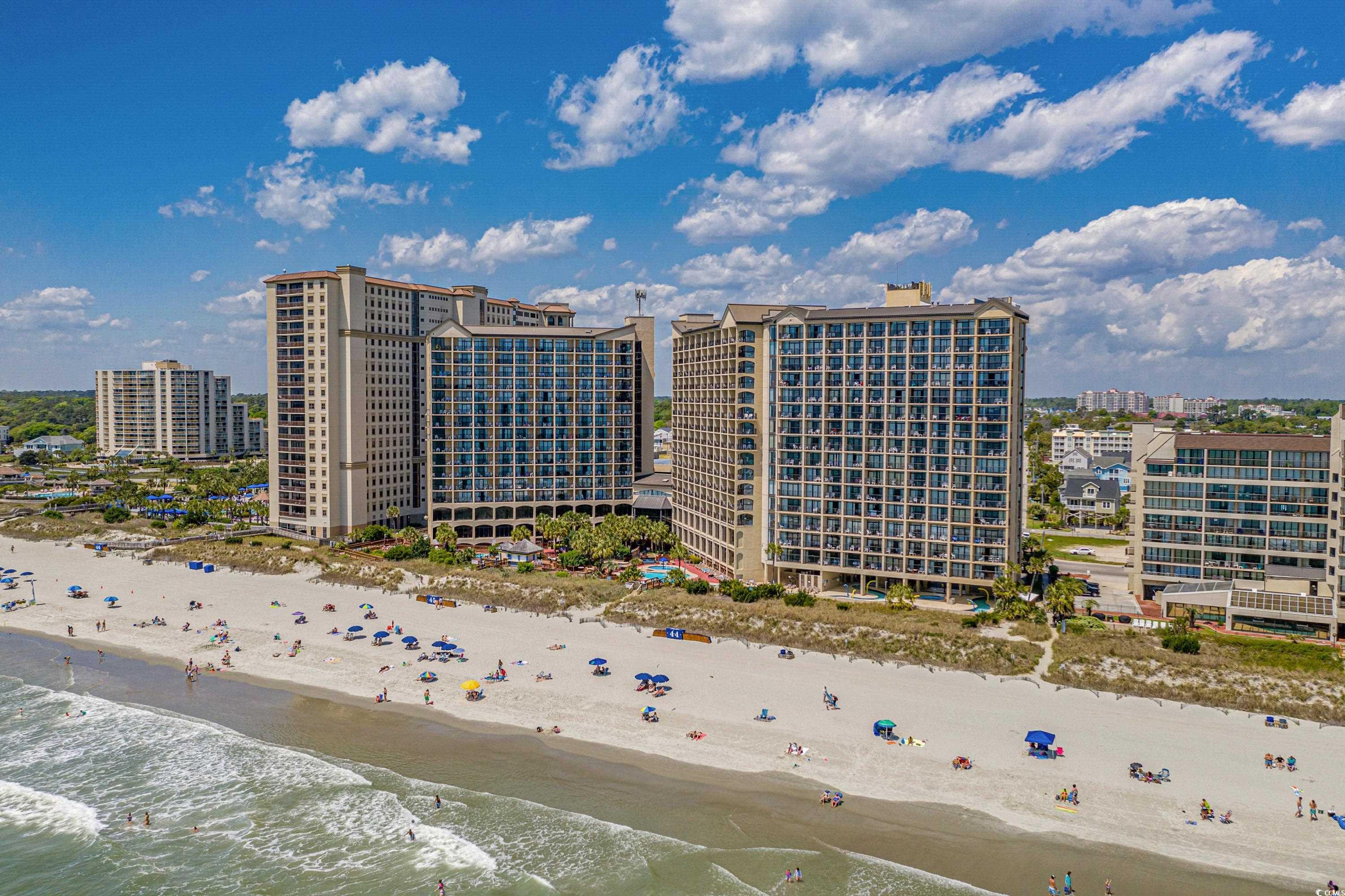 Beachfront condominium towers overlooking a sandy beach and ocean.
