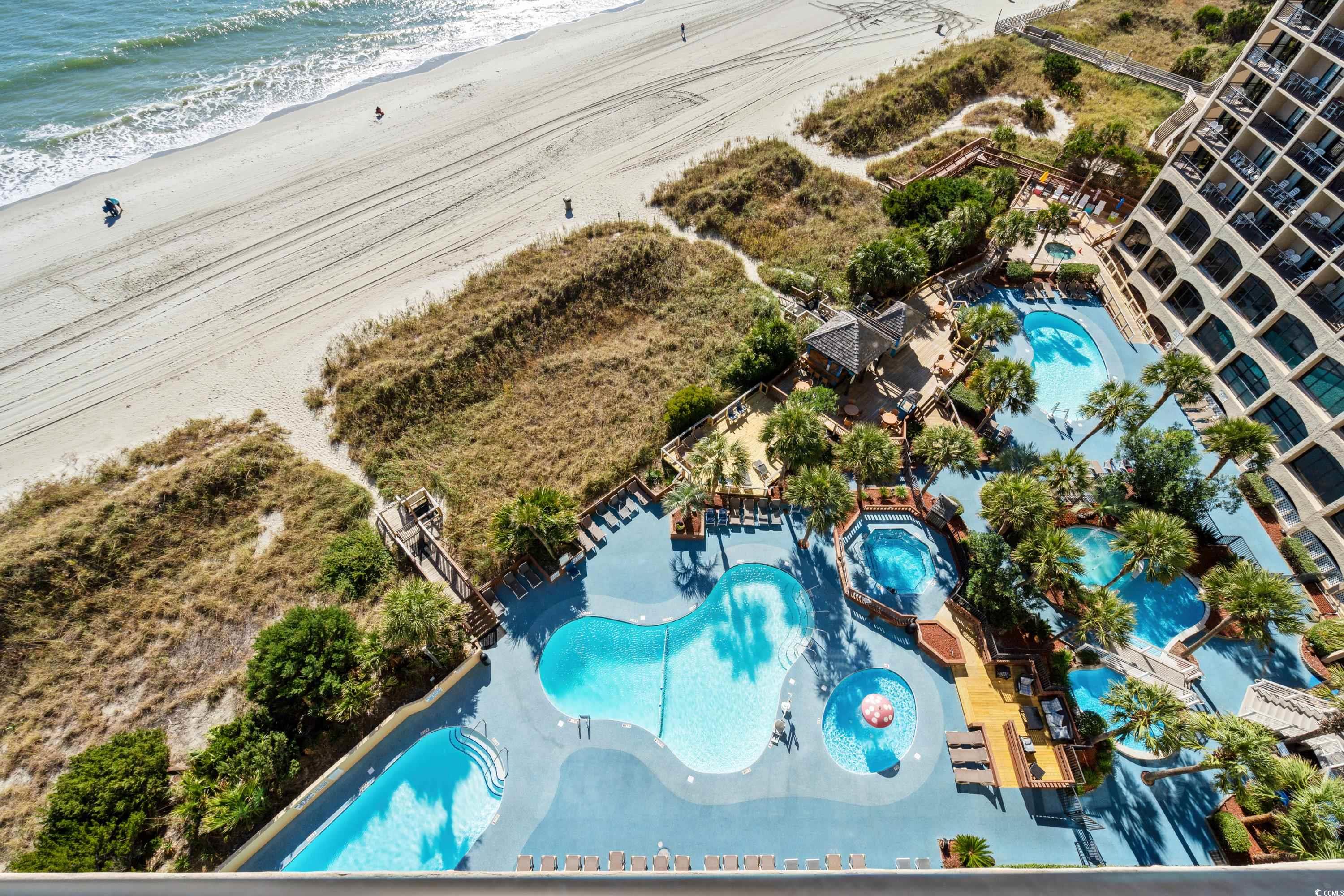 Aerial view of beachfront condominium with multiple pools beside the ocean shoreline.