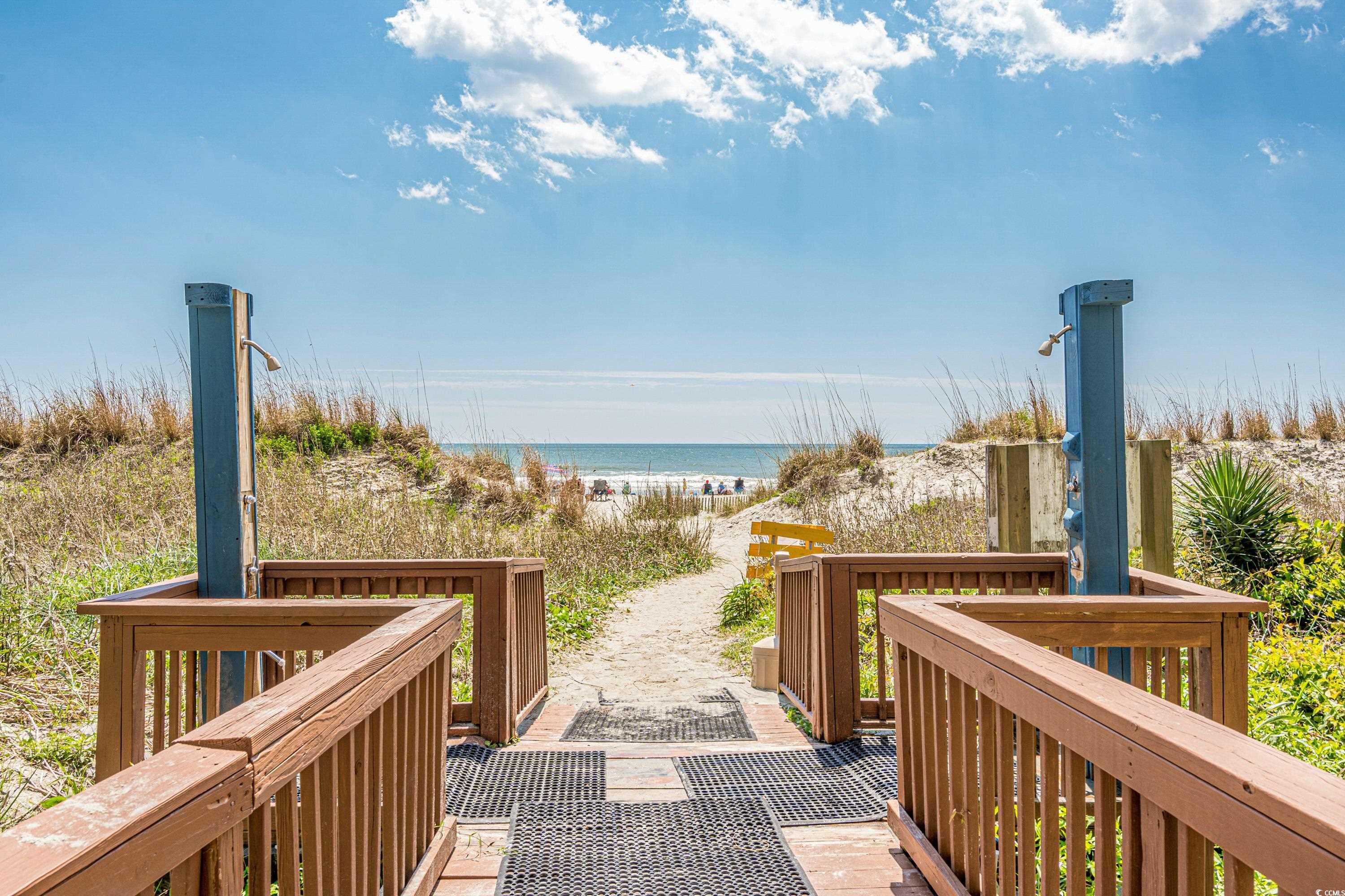 Beach access walkway with outdoor showers leading through dunes to the ocean.